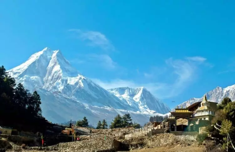 Monastère bouddhiste himalayen au pied de sommets enneigés au Népal sous un ciel bleu