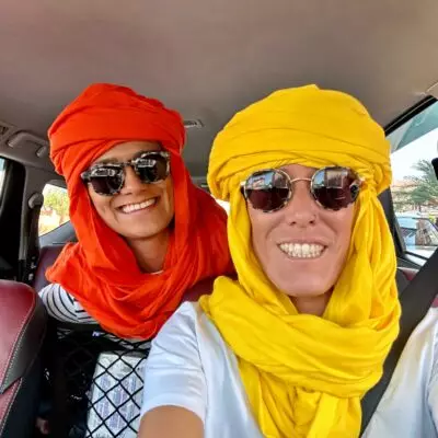 Deux voyageuses portant des chèches traditionnels colorés lors d’un circuit dans le sud du Maroc.