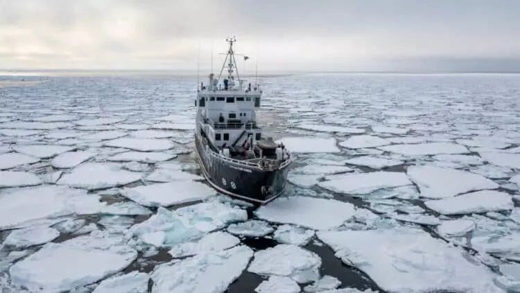 Navire d’expédition naviguant au milieu de la banquise au Spitzberg, entouré de plaques de glace dérivantes en Arctique.