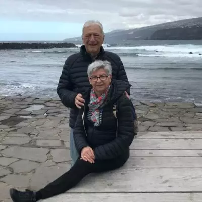 Couple de voyageurs au bord de l’océan sur la côte de Grande Canarie, avec les falaises volcaniques en arrière-plan.