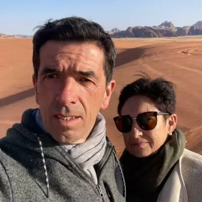 Couple de voyageurs dans le désert du Wadi Rum en Jordanie, entouré de dunes et de formations rocheuses.