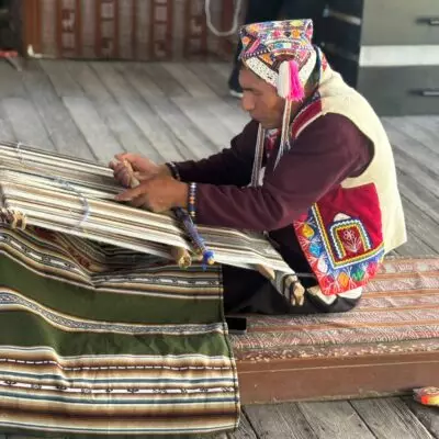 Artisan péruvien en tenue traditionnelle réalisant un tissage andin artisanal au Pérou.