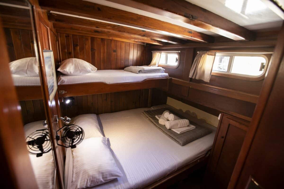 Intérieur de cabine en bois sur voilier avec lits superposés et salle de bain