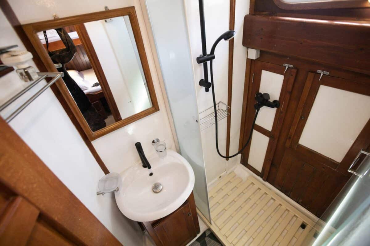Salle de bain compacte dans un yacht avec douche moderne et miroirs.