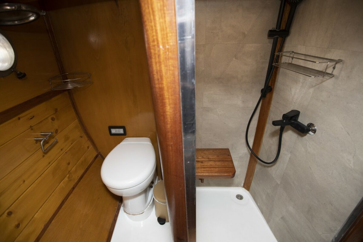 Toilette moderne et douche sur un yacht, avec boiseries et accents en béton.