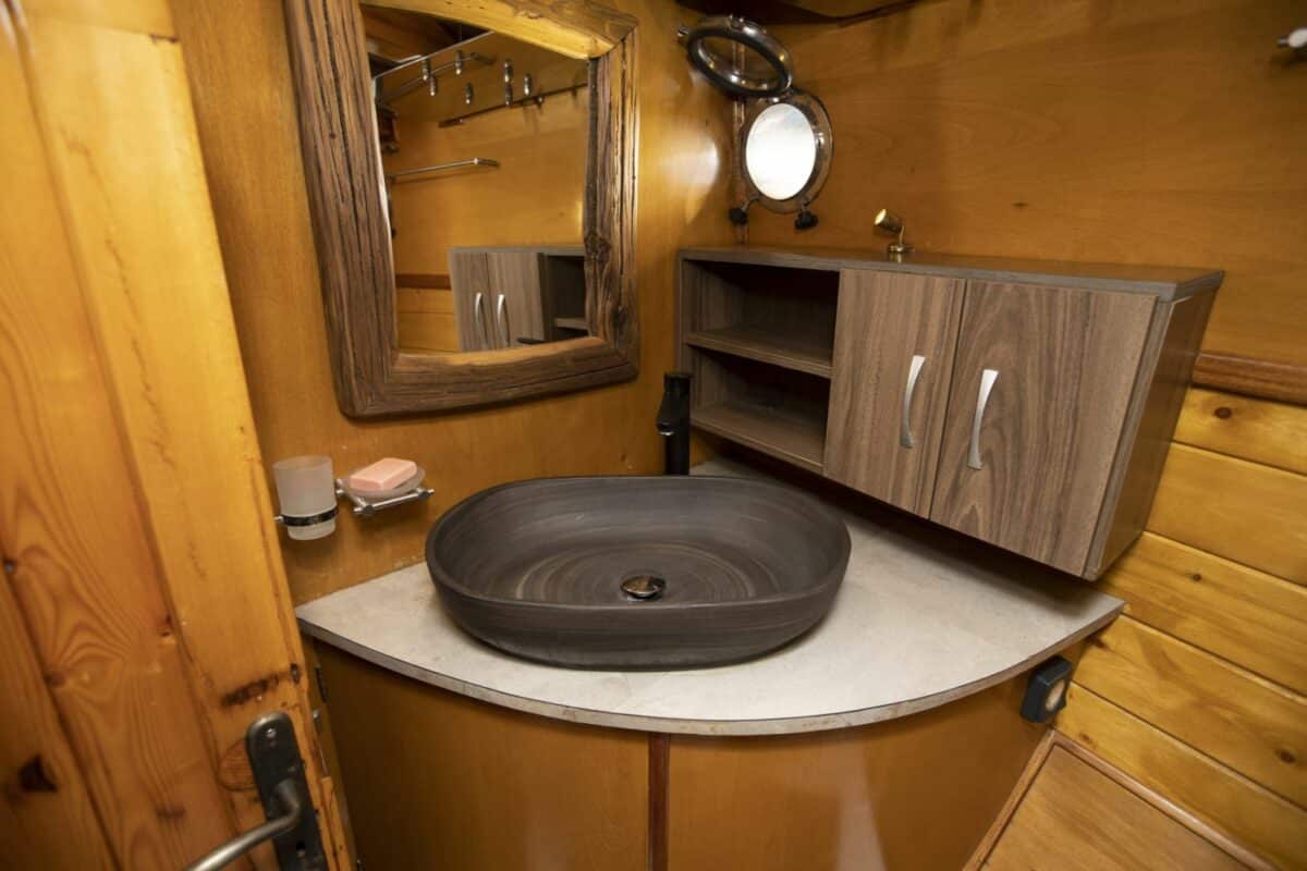 Intérieur d'une salle de bain en bois sur un yacht, avec un lavabo ovale et un miroir.