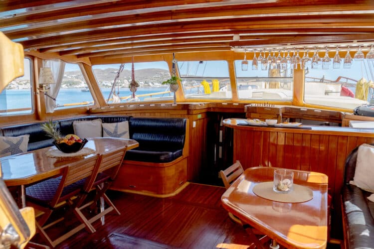 Vue intérieure d'un salon de yacht en bois avec vue sur la mer par des fenêtres panoramiques.