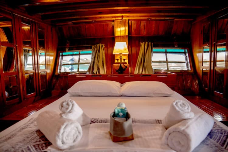Cabine double sur un yacht avec lits jumeaux et fenêtres donnant sur la mer.