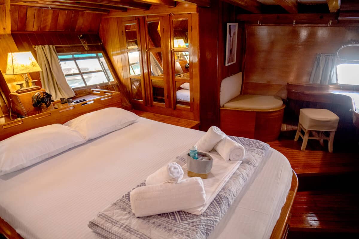 Intérieur d'une cabine de yacht en bois avec un grand lit et des décorations nautiques.
