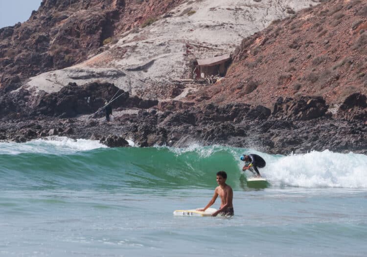 Surfeur surfant une vague près des falaises rocheuses du Maroc.