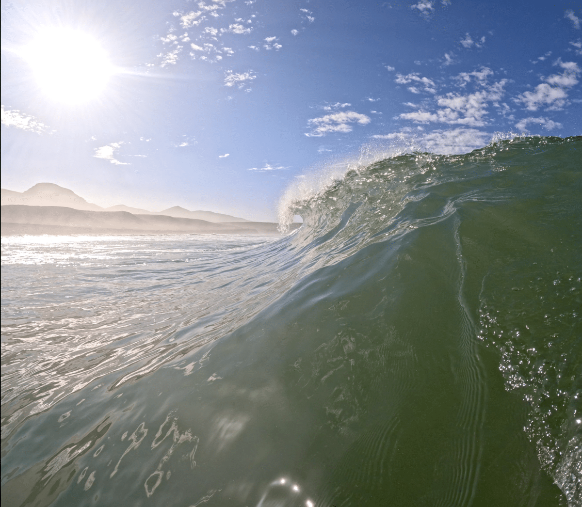 Sunlit wave curling towards the shore in Morocco.