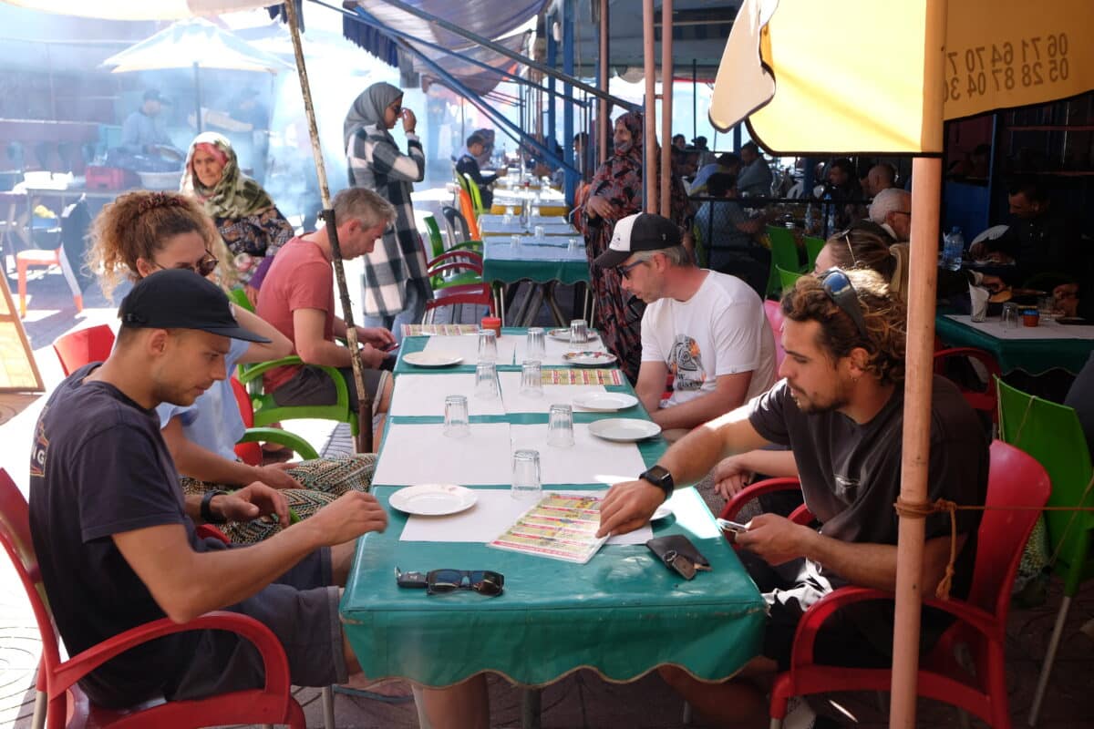 Surfeurs dégustant un repas dans un marché local au Maroc.