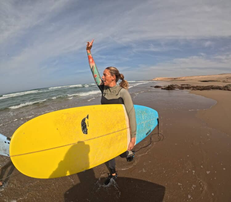 Surfeuse levant le bras après une session réussie - Plage marocaine.