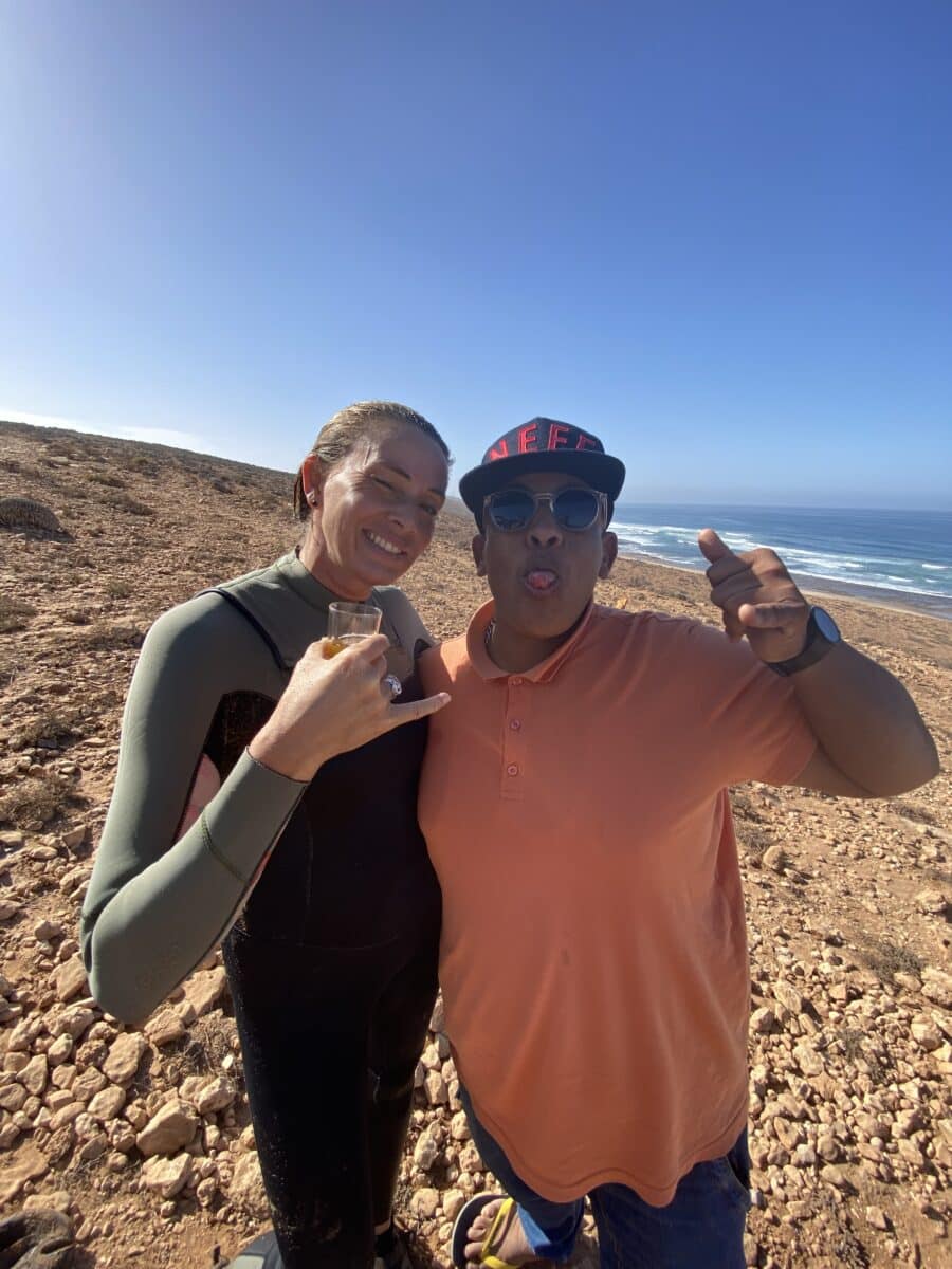 Surfeuse et guide local souriant devant l’océan marocain