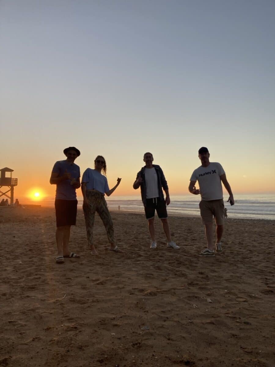 Groupe de personnes posant sur une plage marocaine au coucher du soleil.