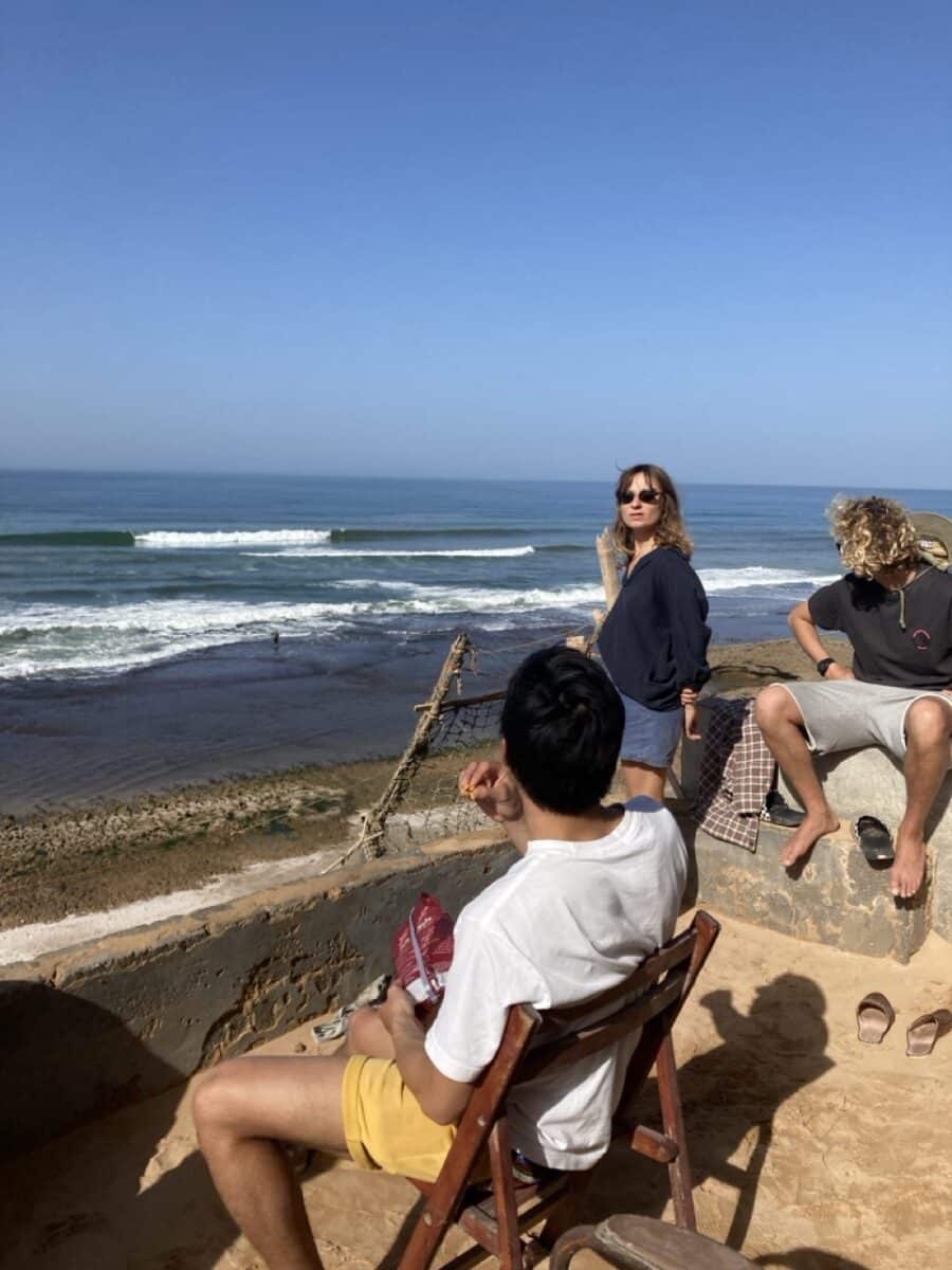 Surfeurs se relaxant sur une terrasse avec vue sur l’océan.