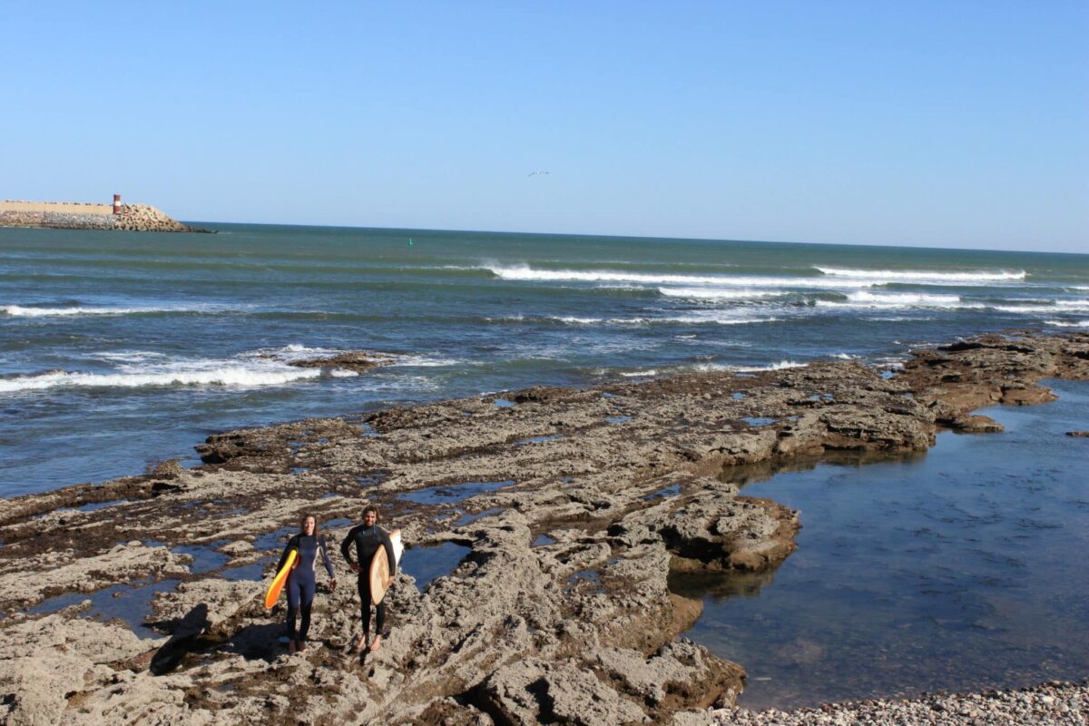 Surfeurs marchant sur des rochers près de l’océan.