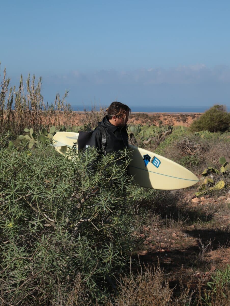 Surfeur explorant une plage isolée sur la côte marocaine.