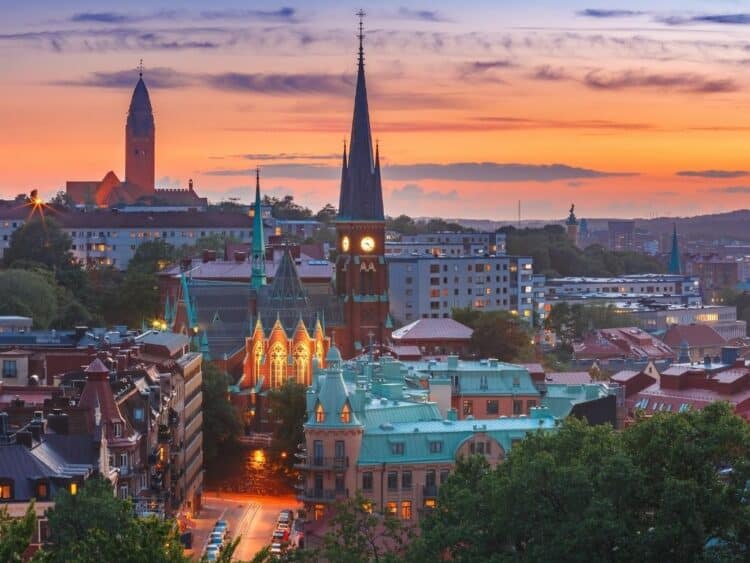 Vue panoramique de Göteborg au crépuscule avec des bâtiments éclairés et des églises en arrière-plan.