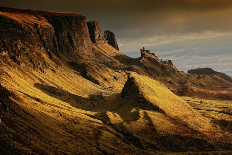 Paysage montagneux dramatique des Highlands en Écosse, avec falaises érodées et vallées verdoyantes.