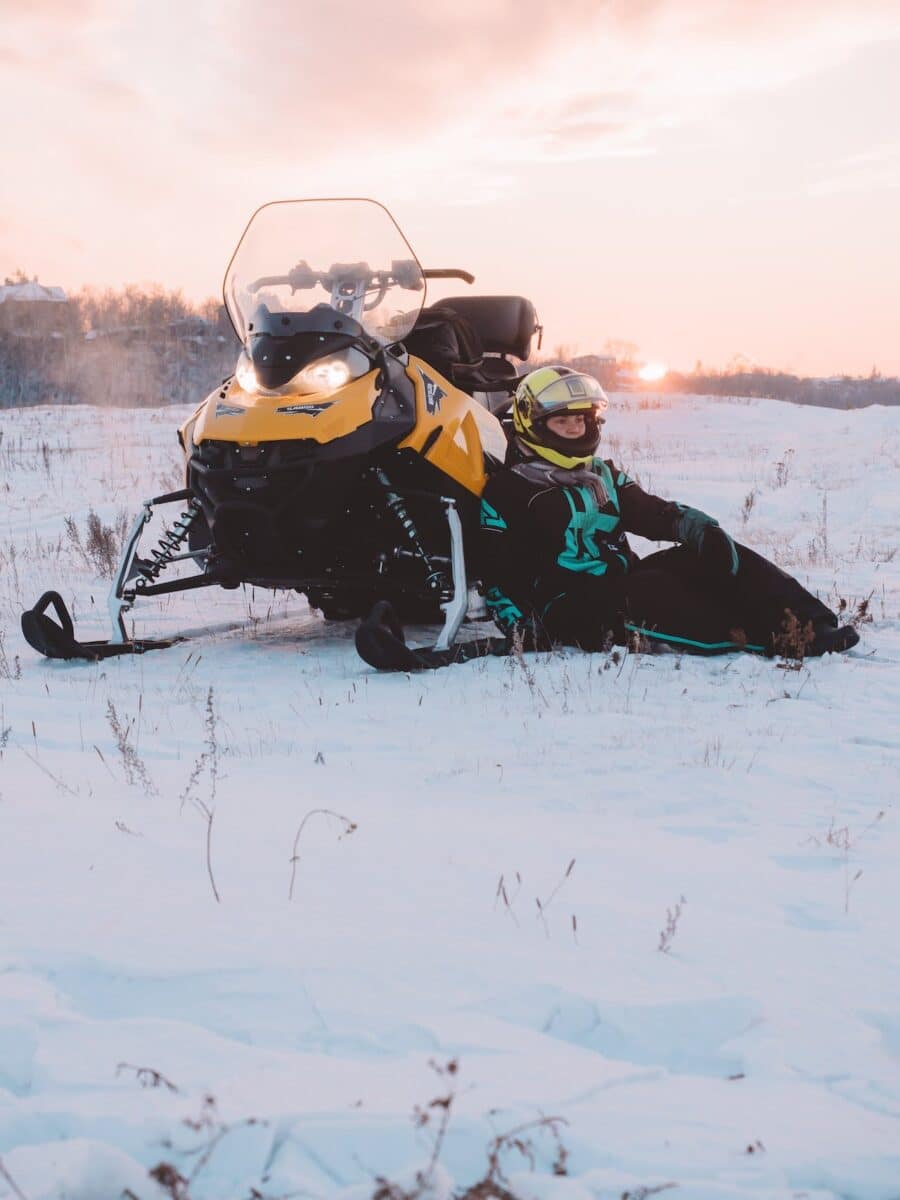 Personnes faisant un safari en motoneige dans la neige au coucher du soleil