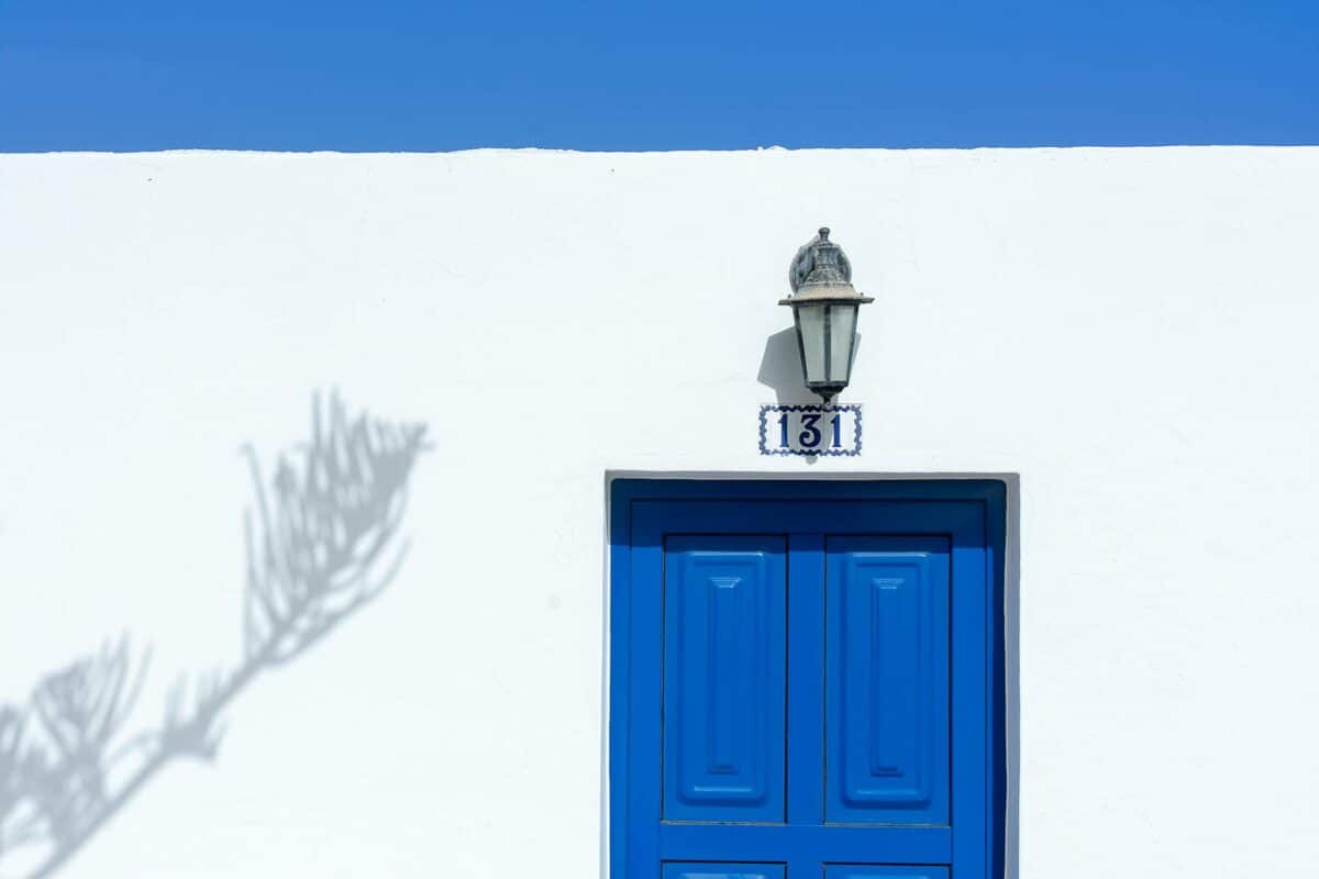 Maison traditionnelle de style des Îles Canaries avec une porte frappante bleue et un mur blanc.