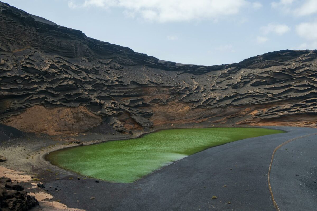 Lagune verte unique située dans un cratère volcanique sombre aux Îles Canaries.