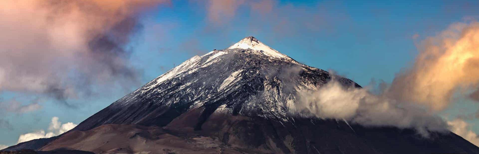 Sommet enneigé du Mont Teide contre un ciel vibrant au coucher du soleil aux Îles Canaries.