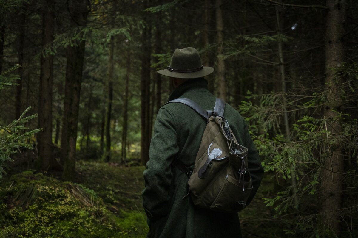 Homme avec un sac à dos marchant dans une forêt dense.