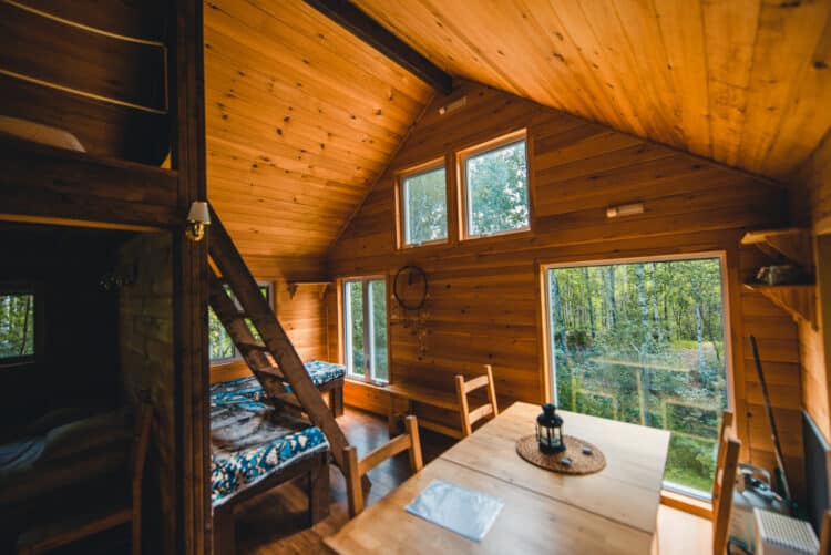 Intérieur chaleureux d'une cabane en bois avec vue sur la forêt du Québec.