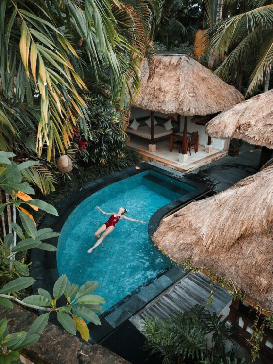 Une femme flottant dans une piscine privée entourée de végétation tropicale à Bali.