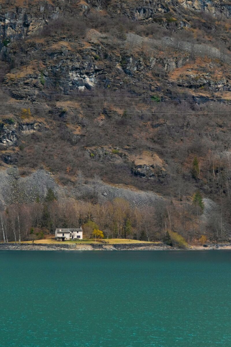 Petit chalet isolé au bord d'un lac bleu avec des falaises rocheuses en arrière-plan