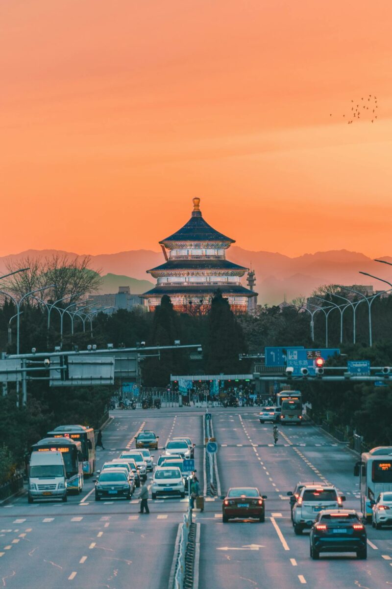 Vue du Temple du Ciel à Pékin au coucher du soleil, avec des montagnes en arrière-plan.