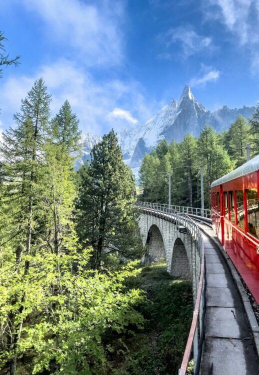 Train traversant un pont en pierre dans un paysage de montagnes avec forêts