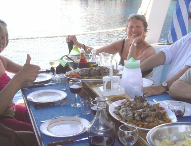 Repas méditerranéen gourmet servi sur le pont d'un yacht de luxe, avec des invités savourant le festin