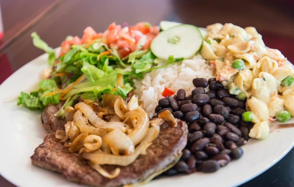 Plat traditionnel costaricien avec du riz, des haricots noirs, de la salade et de la viande grillée.