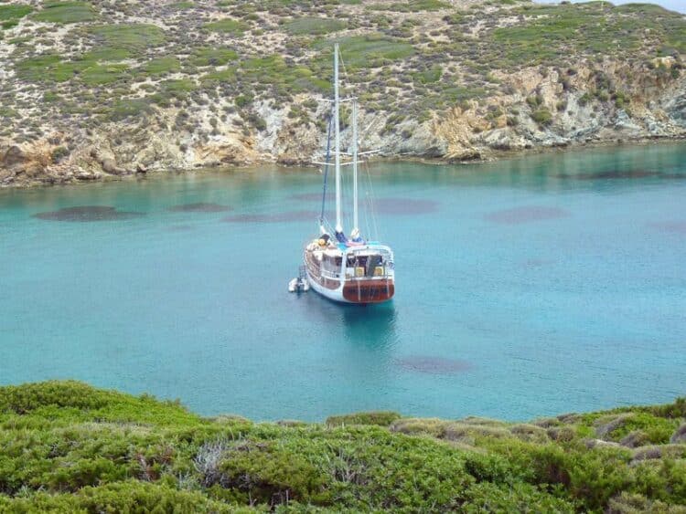 Yacht de luxe ancré dans une baie turquoise entourée de falaises rocheuses et de verdure luxuriante