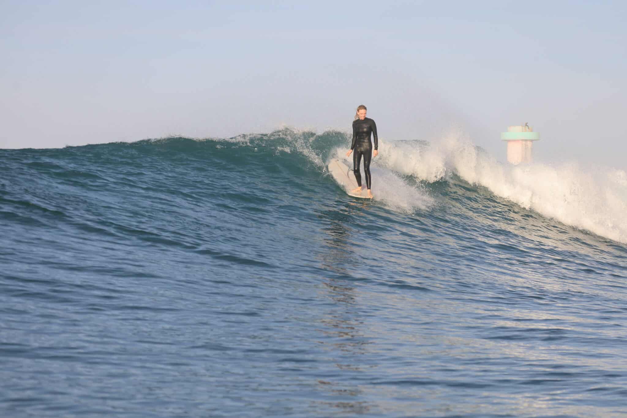 Surfeur expérimenté sur une vague à Imsouane, Maroc, près du phare emblématique.