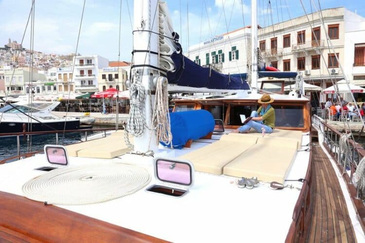 Personne se relaxant sur le pont d'un yacht avec vue sur un port grec pittoresque