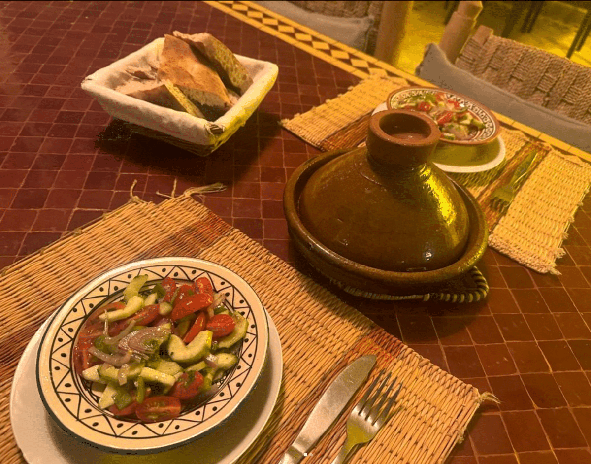 Repas marocain traditionnel avec tajine et salade fraîche sur une table décorée.