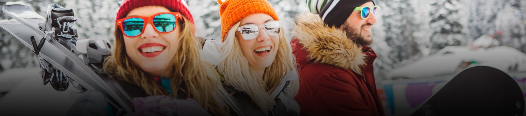 Personnes souriantes en vêtements d'hiver, prêtes pour des activités hivernales dans un paysage enneigé.