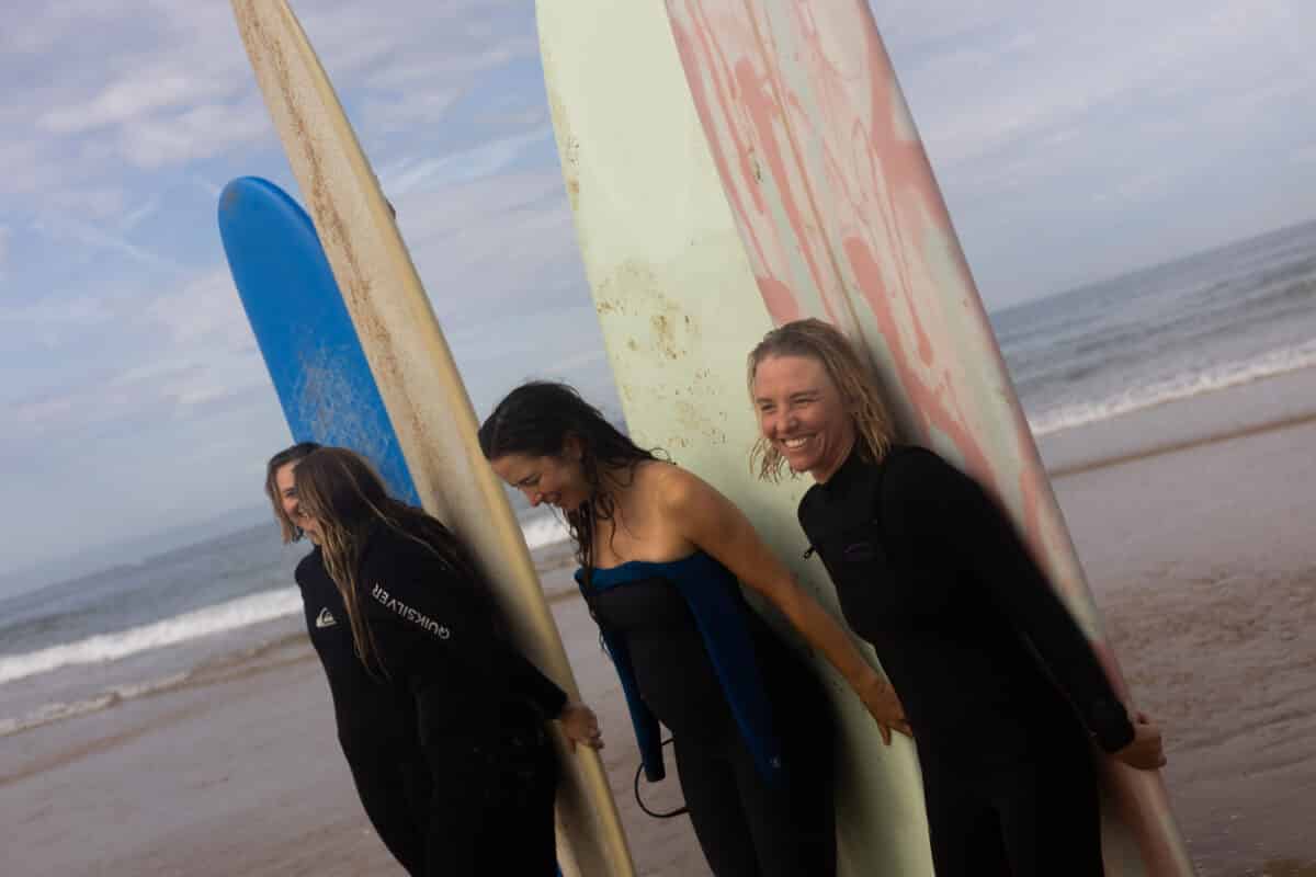 Groupe de surfeuses portant des planches sur la plage d’Imsouane.