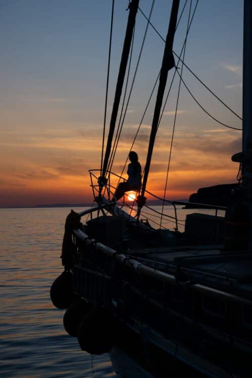 Silhouette d'une femme sur un voilier au coucher de soleil