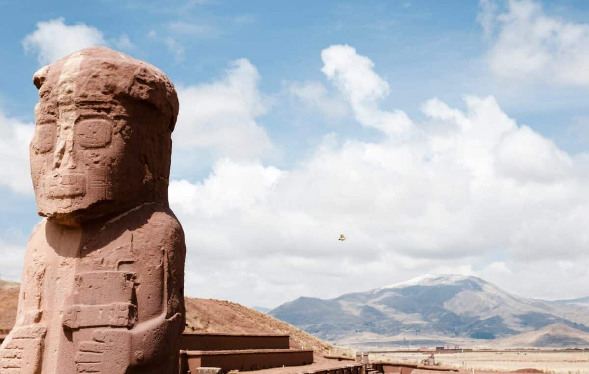 Statue monolithique au site archéologique de Tiwanaku, entourée de montagnes.