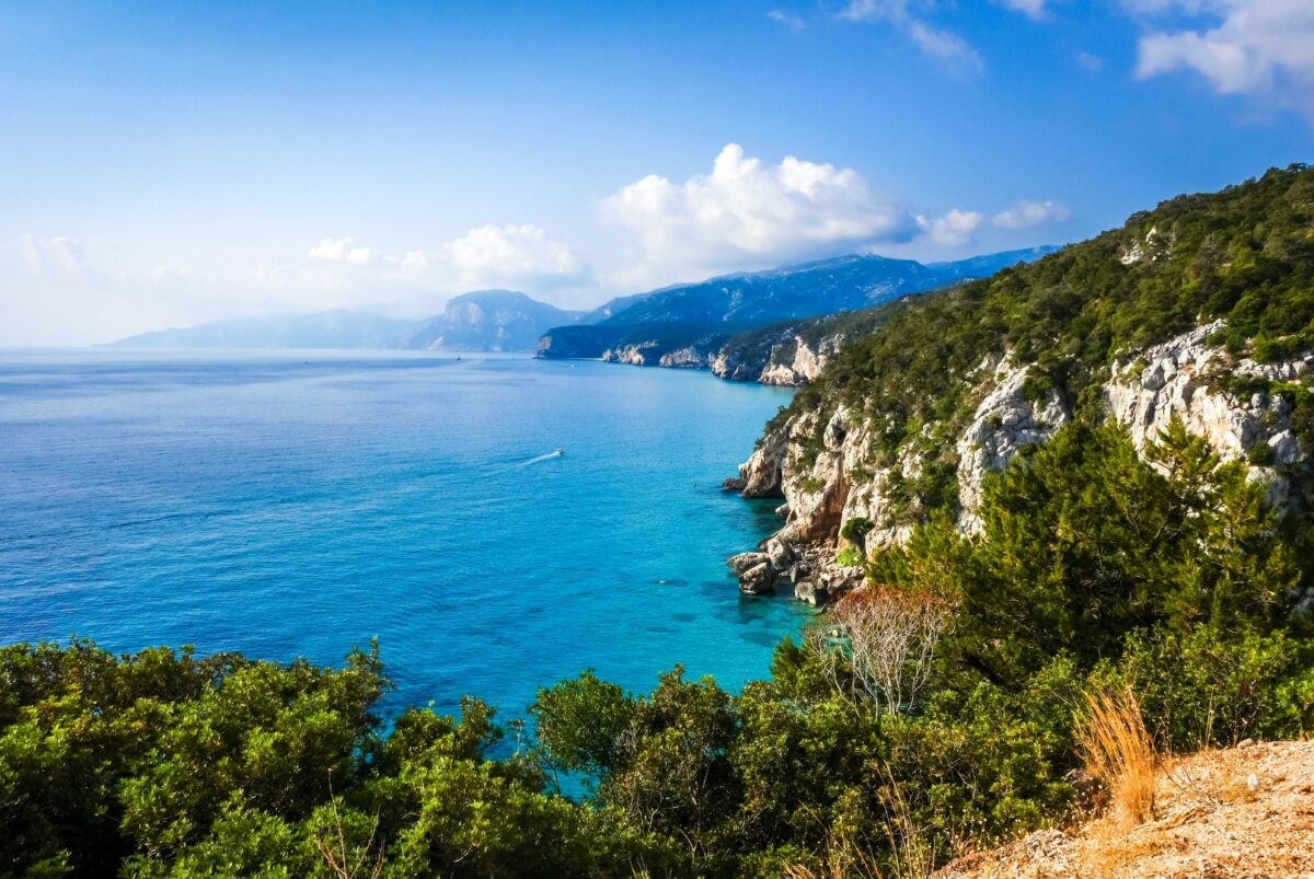 Vue panoramique sur la mer cristalline et les falaises verdoyantes de Sardaigne.