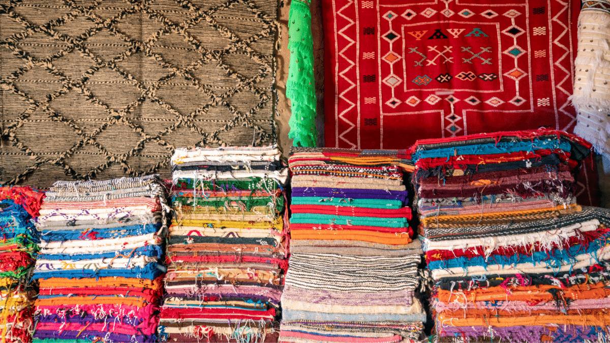 Étalage de tapis berbères colorés dans un marché marocain.