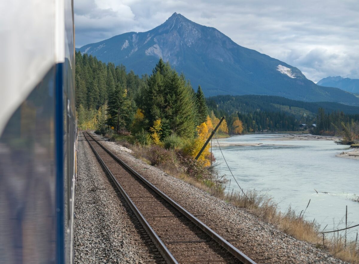 Le chemin de fer bordant une rivière avec des montagnes en arrière-plan au Canada.