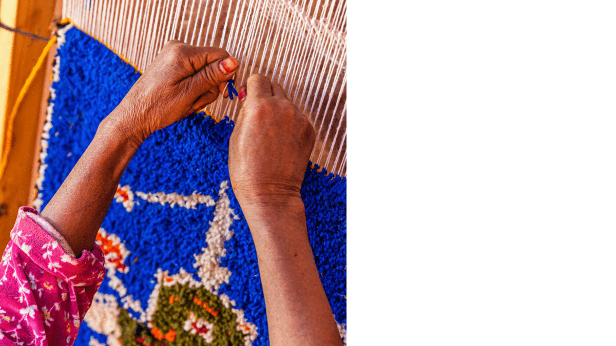 Main d’une femme tissant un tapis berbère coloré.