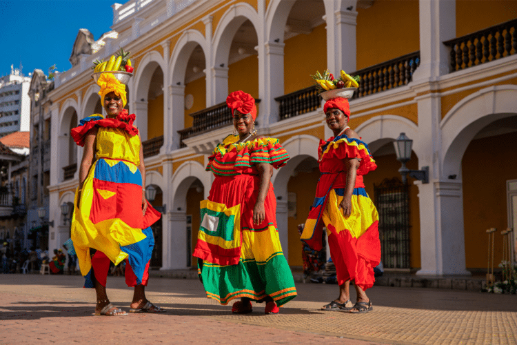 Femmes colombiennes en costumes traditionnels devant une architecture coloniale.