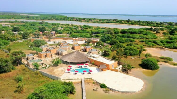 Vue aérienne d’un complexe avec des lodges au bord d’une lagune au Sénégal.